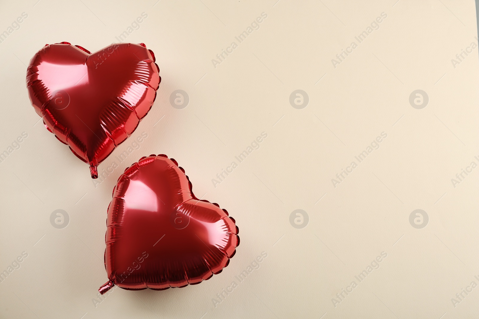 Photo of Red heart shaped balloons on beige background, flat lay with space for text. Saint Valentine's day celebration