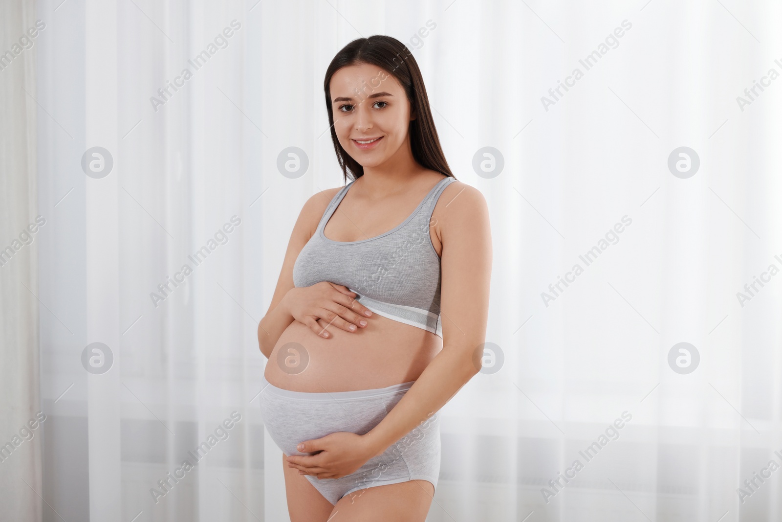 Photo of Beautiful pregnant woman in comfortable maternity underwear indoors