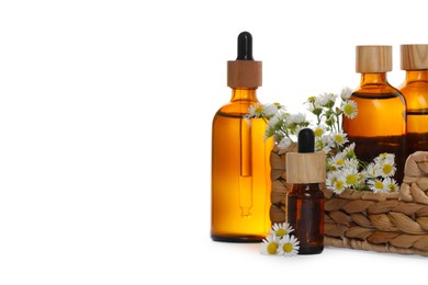 Photo of Bottles of chamomile essential oil and flowers on white background