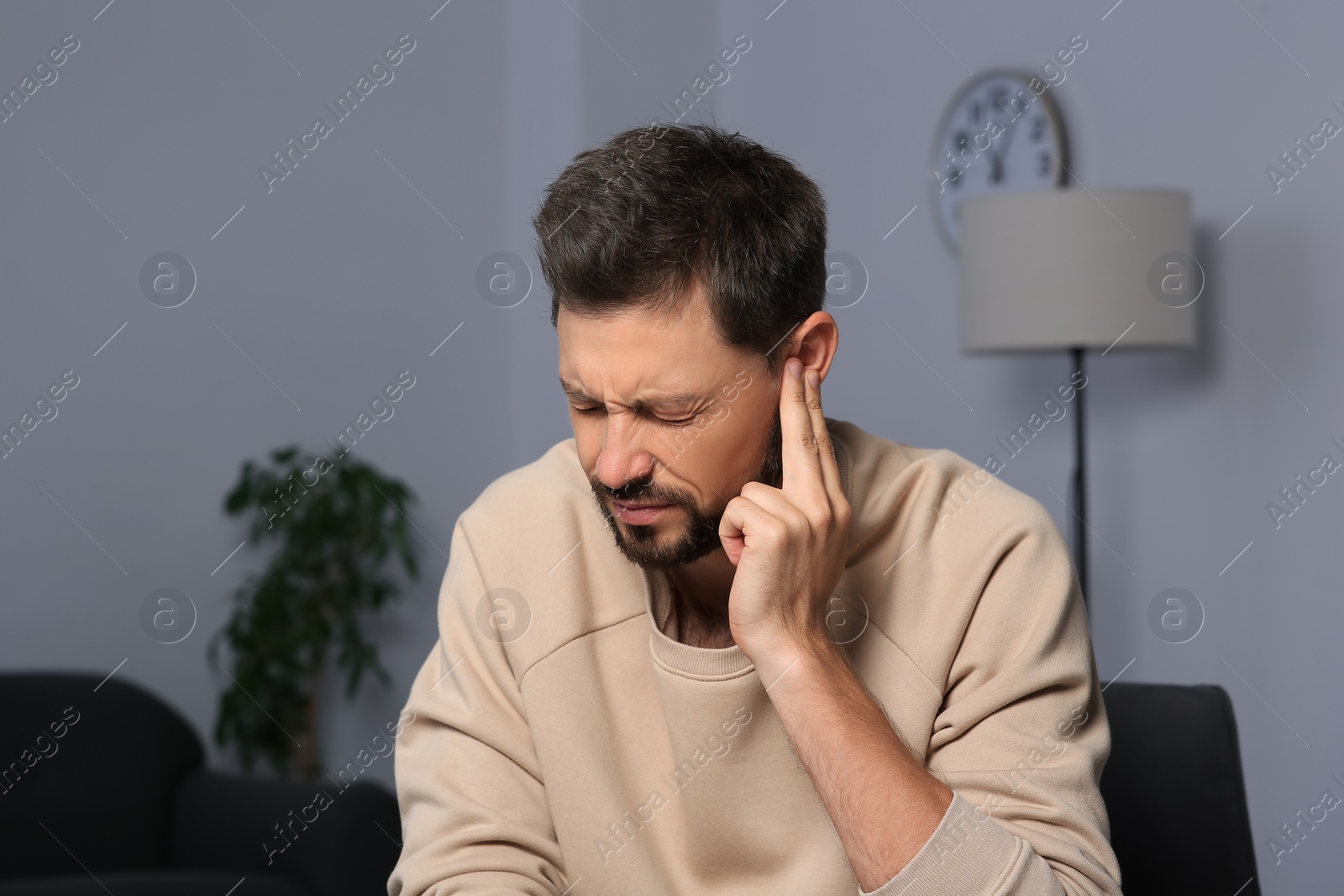 Photo of Man suffering from ear pain on in room