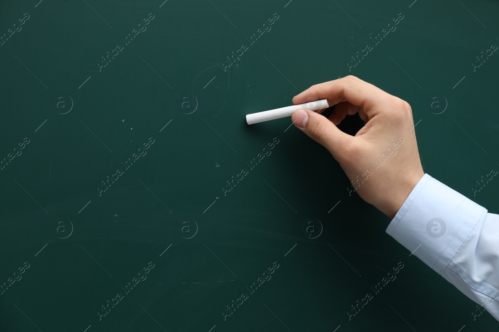 Photo of Teacher writing with chalk on green chalkboard, closeup. Space for text