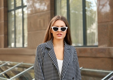 Photo of Young woman wearing stylish sunglasses on city street