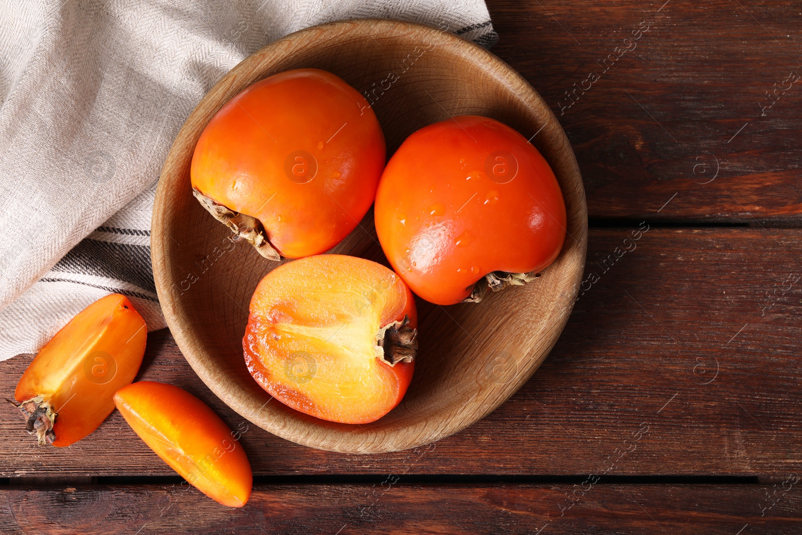 Photo of Delicious ripe persimmons on wooden table, top view