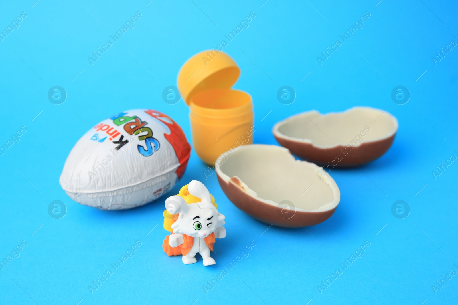 Photo of Slynchev Bryag, Bulgaria - May 25, 2023: Kinder Surprise Eggs, plastic capsule and toy bunny on light blue background