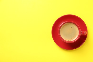 Photo of Tasty coffee in cup on yellow background, top view. Space for text