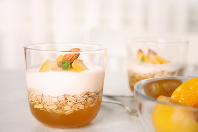 Tasty peach dessert with yogurt and granola on light table. Space for text