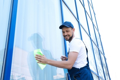 Male worker washing window glass from outside