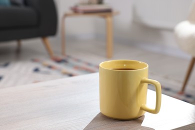 Yellow mug of tea on wooden table indoors, space for text