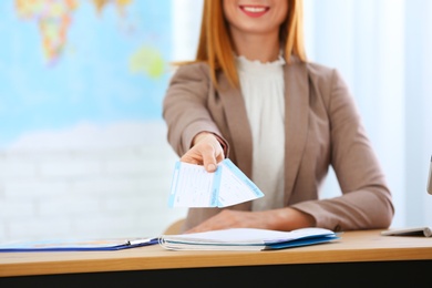 Photo of Female consultant holding tickets in travel agency, closeup