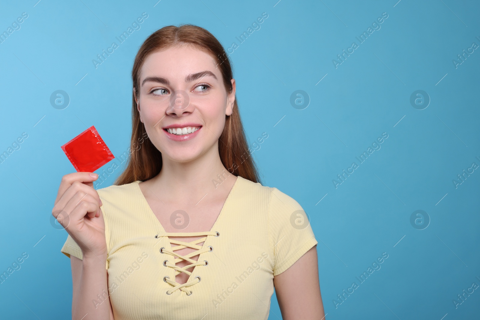Photo of Woman holding condom on turquoise background, space for text. Safe sex