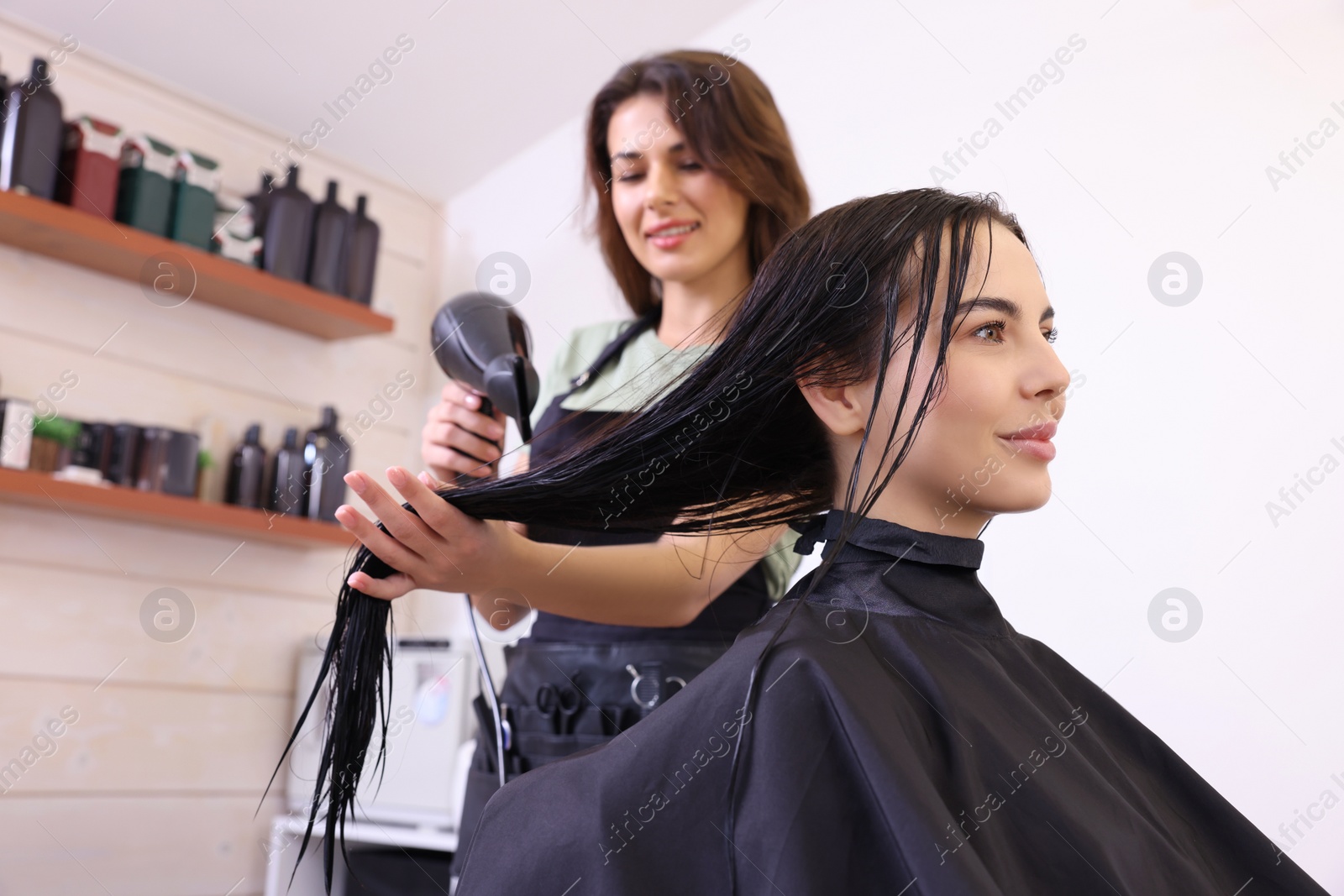 Photo of Hairdresser drying woman's hair in beauty salon