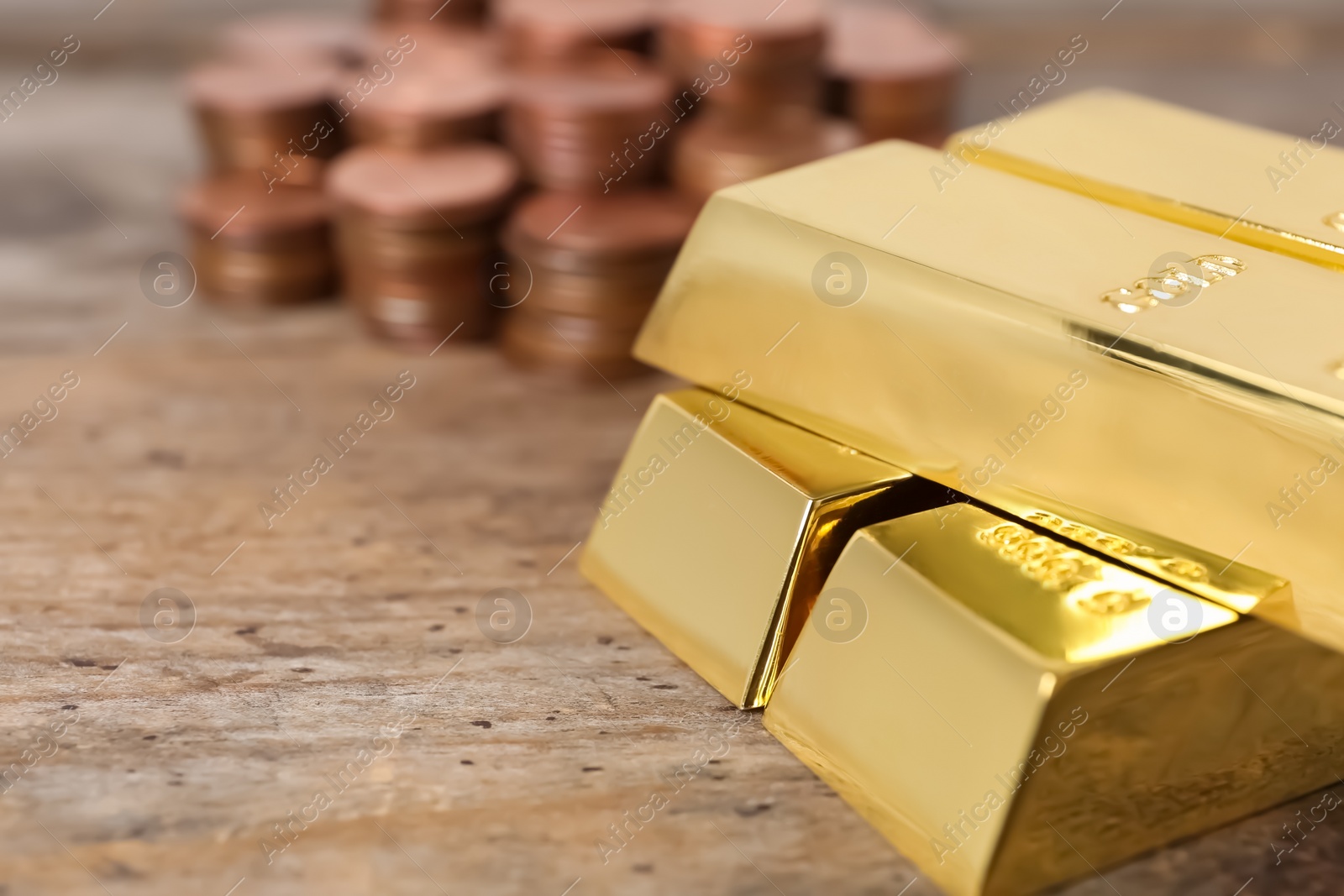 Photo of Stacked gold bars and coins on wooden table, closeup. Space for text