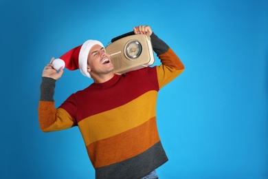 Photo of Happy man with vintage radio on blue background. Christmas music