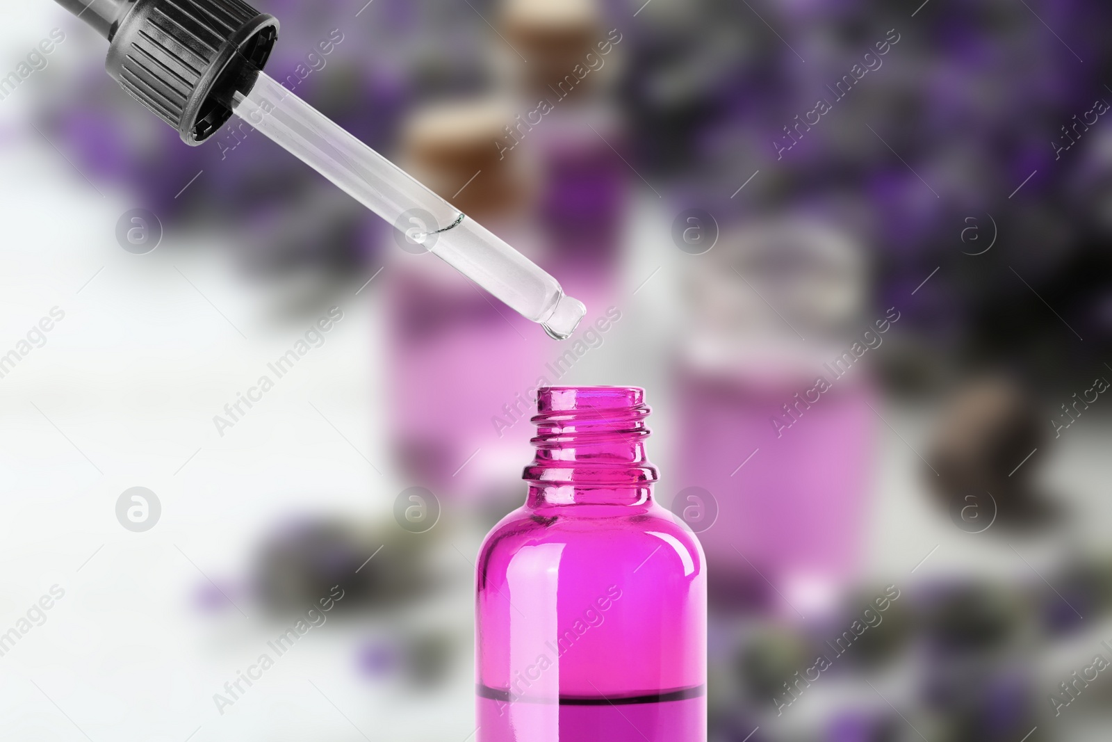 Image of Little bottle with essential oil and dropper against blurred background 