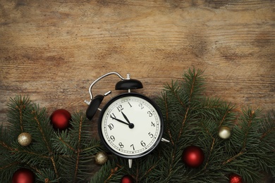 Alarm clock and Christmas decor on wooden background, flat lay with space for text. New Year countdown