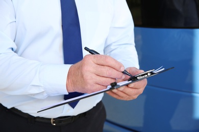 Professional driver with clipboard near bus. Passenger transportation