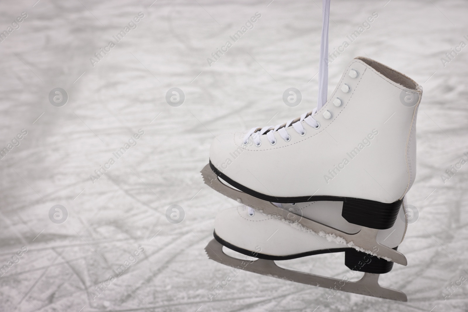 Photo of Pair of figure skates hanging over ice, space for text