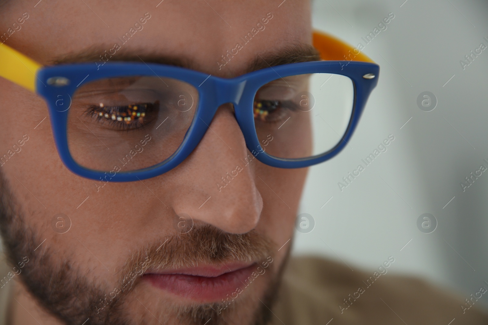 Photo of Young man wearing glasses on blurred background, closeup. Ophthalmology service