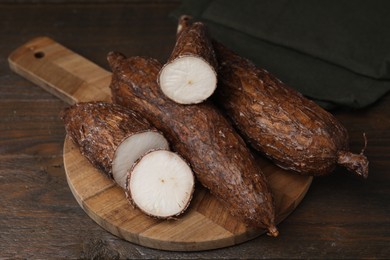 Whole and cut cassava roots on wooden table