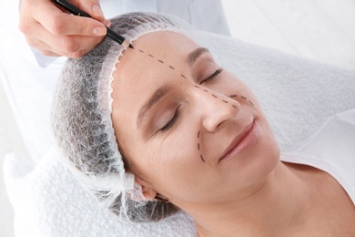 Photo of Doctor marking mature woman face before cosmetic surgery in clinic