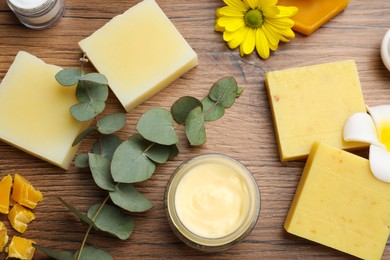 Flat lay composition with beeswax and cosmetic products on wooden table