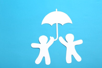 Photo of Paper silhouettes of people under umbrella on color background, flat lay. Life insurance concept