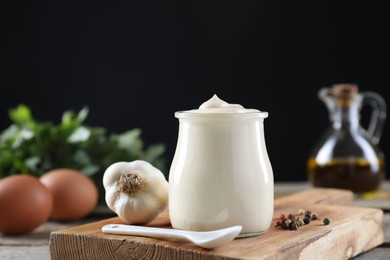 Photo of Fresh mayonnaise sauce in glass jar and ingredients on wooden table, closeup