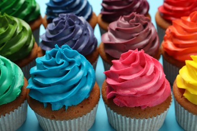 Photo of Many delicious colorful cupcakes on light blue background, closeup