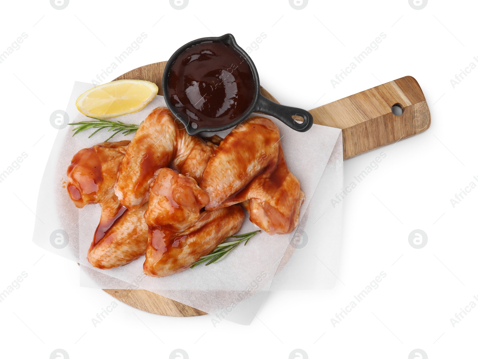 Photo of Board with marinade, raw chicken wings, rosemary and lemon isolated on white, top view