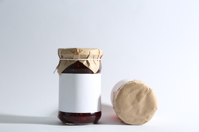 Photo of Glass jars with raspberry jam on white background