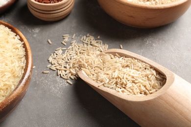 Photo of Brown and other types of rice on grey table, closeup view