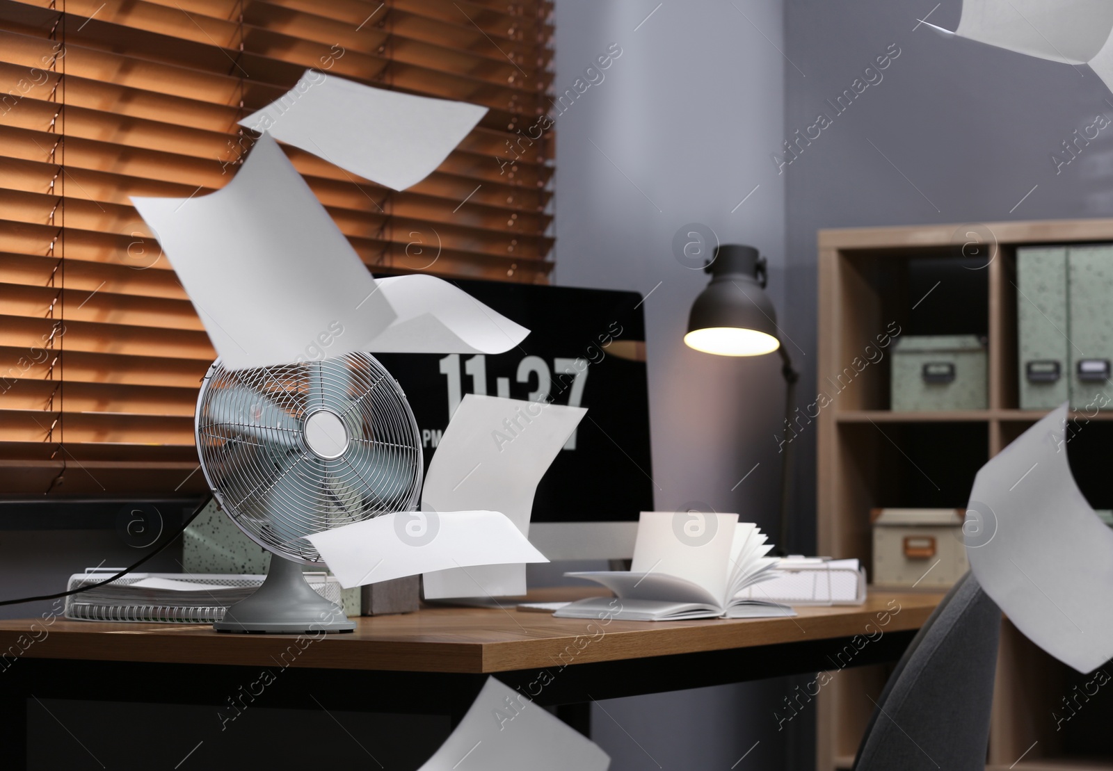 Photo of Modern electric fan and flying paper in office