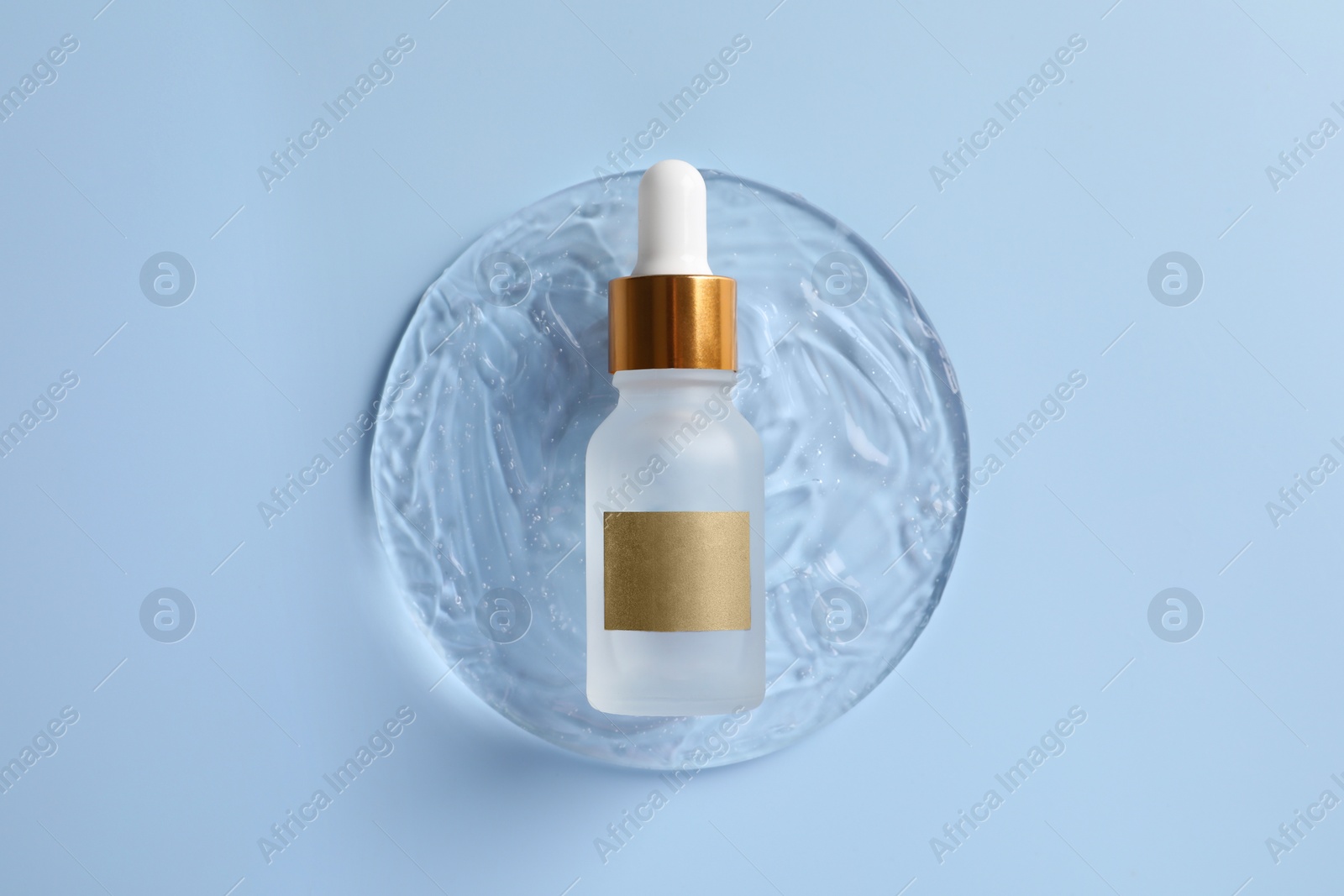 Photo of Bottle of cosmetic serum on light blue background, top view