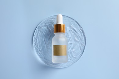 Photo of Bottlecosmetic serum on light blue background, top view