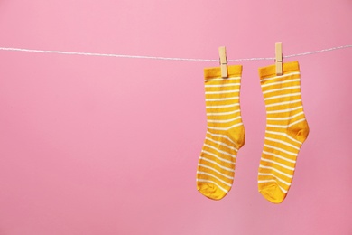 Cute socks on laundry line against color background. Space for text