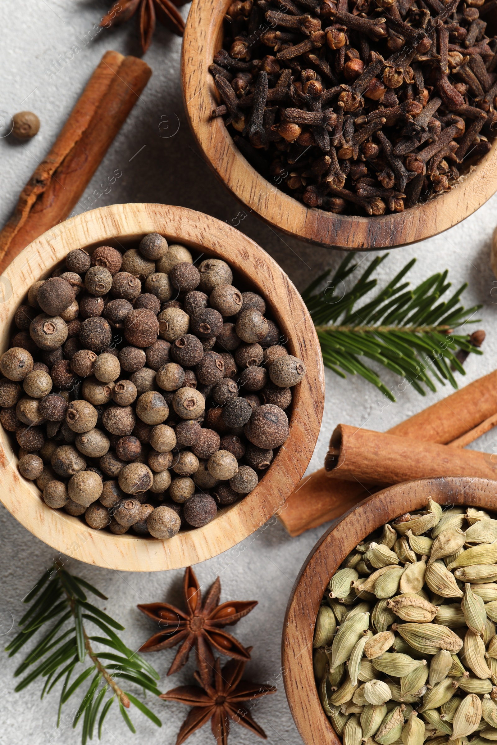 Photo of Different aromatic spices and fir branches on light textured table, flat lay