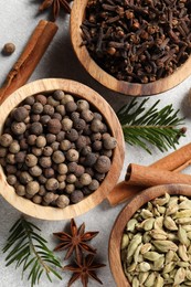 Photo of Different aromatic spices and fir branches on light textured table, flat lay
