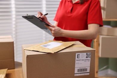 Parcel packing. Post office worker with clipboard indoors, closeup