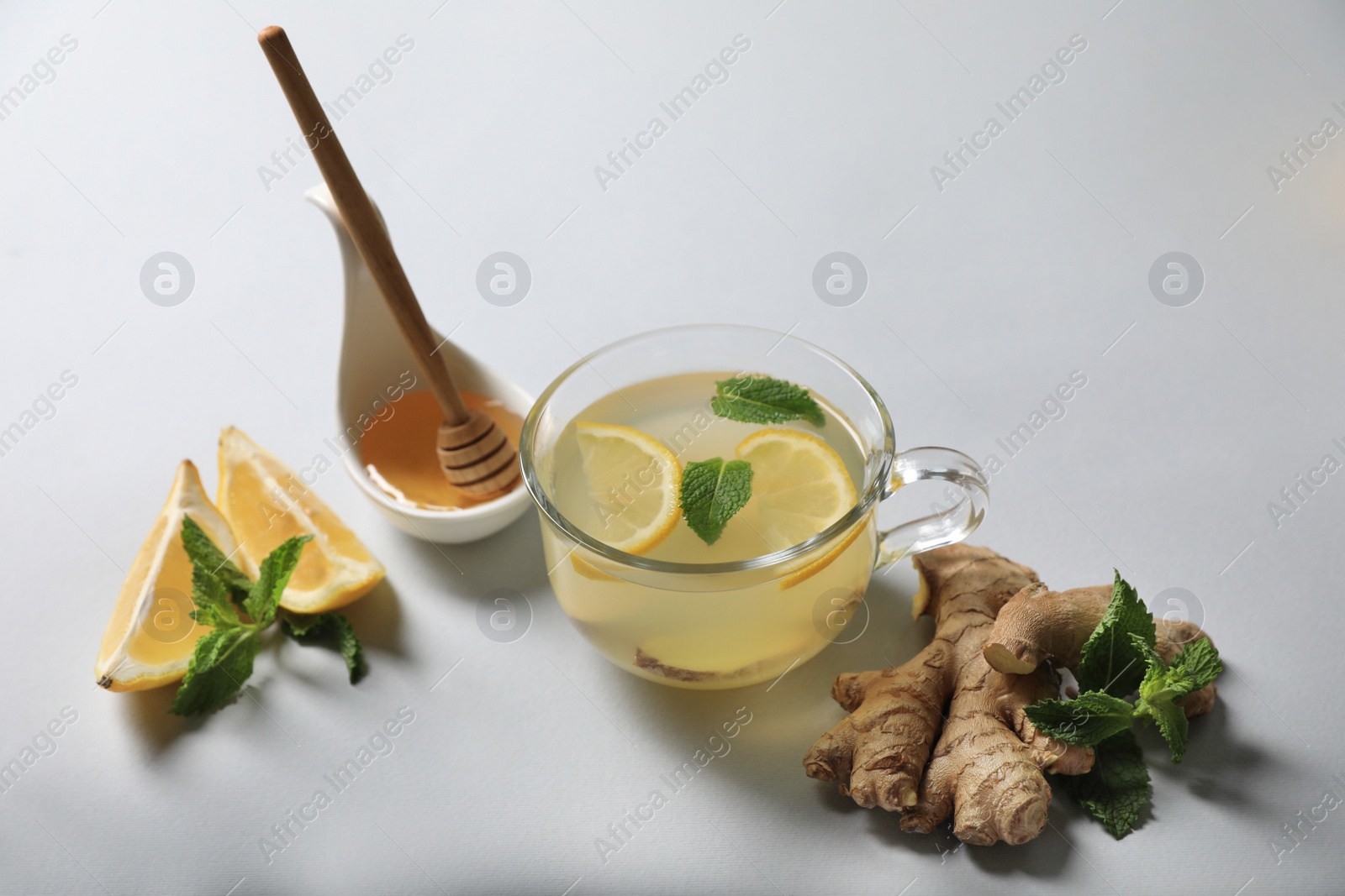 Photo of Delicious ginger tea and ingredients on light grey background