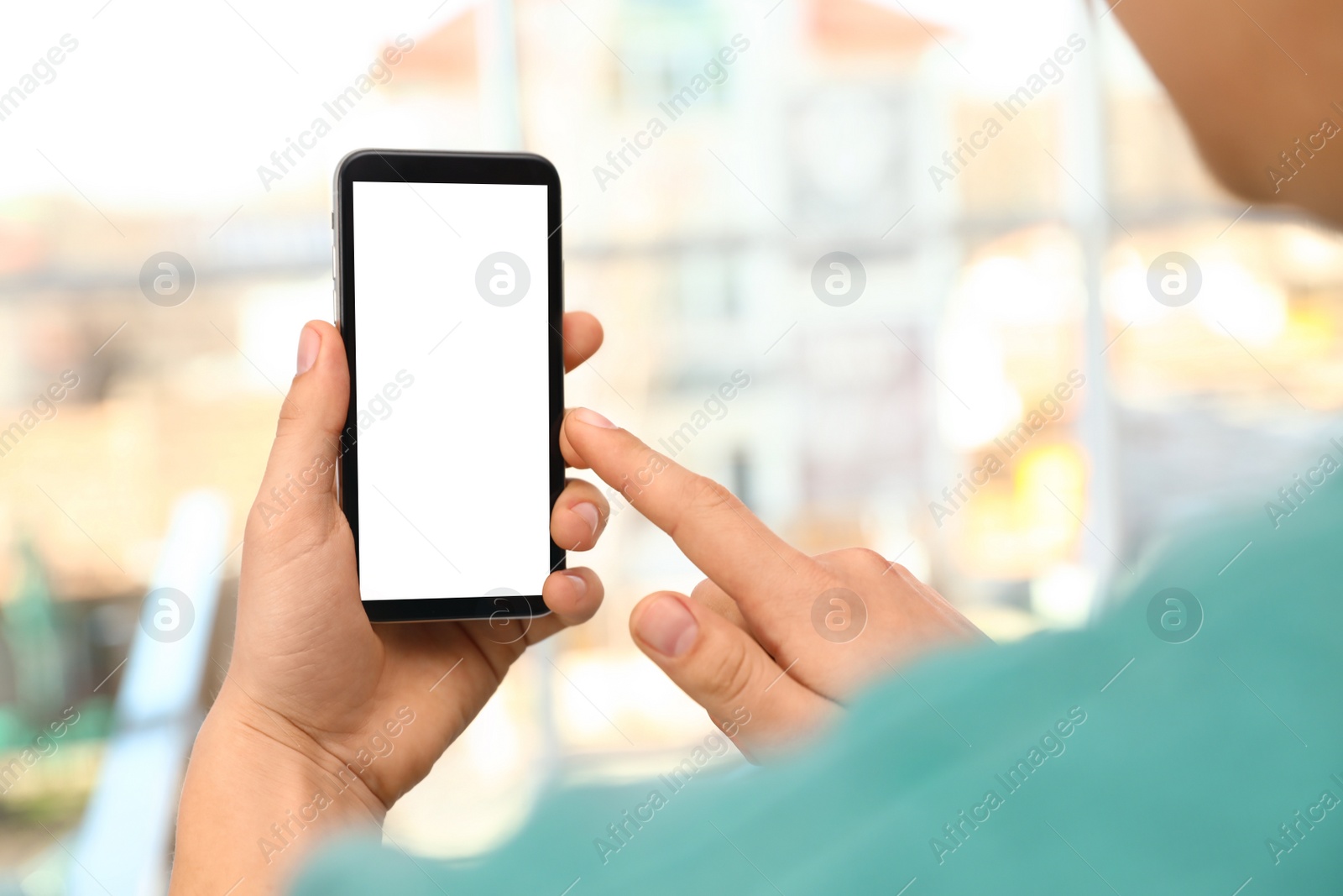 Photo of Man holding smartphone with blank screen on blurred background, closeup of hands. Space for text