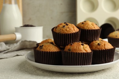 Photo of Delicious sweet muffins with chocolate chips on light textured table, closeup