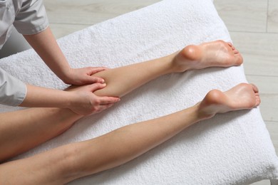 Photo of Woman receiving leg massage in spa salon, closeup