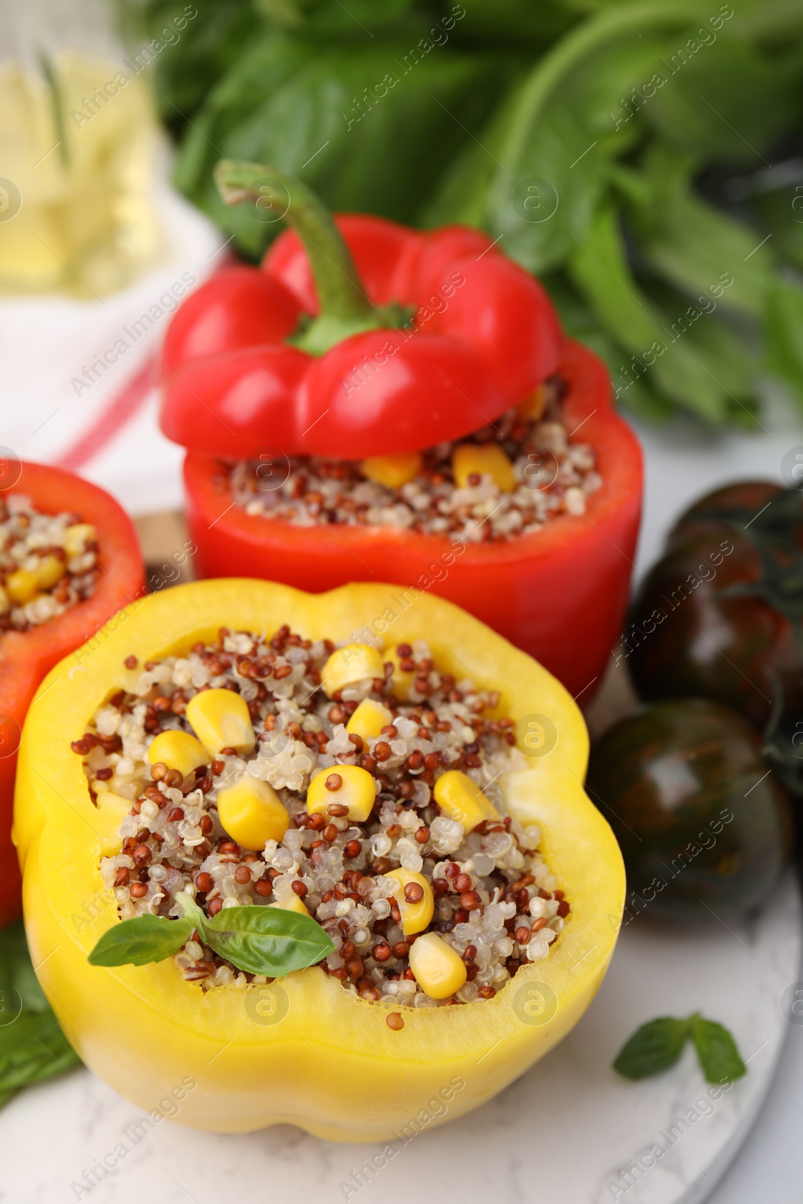 Photo of Quinoa stuffed bell peppers and basil on white table, closeup