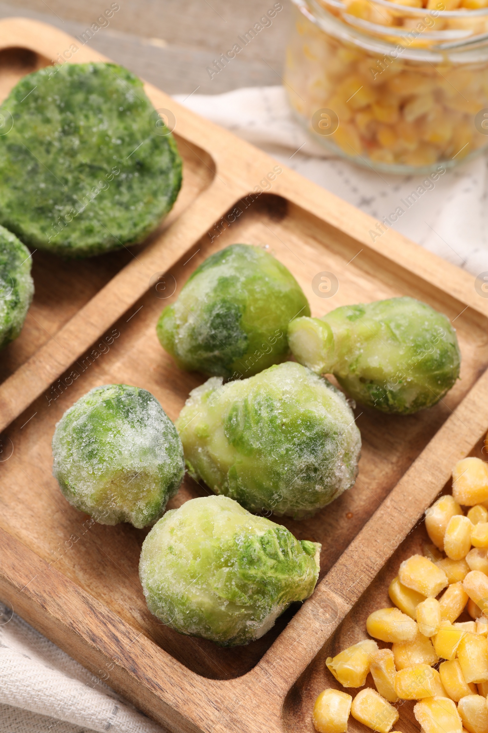 Photo of Wooden tray with different frozen vegetables on table, closeup