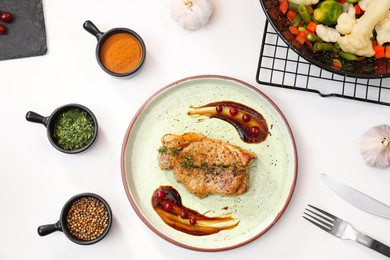 Photo of Flat lay composition with plate of delicious meat on white table in studio. Food stylist