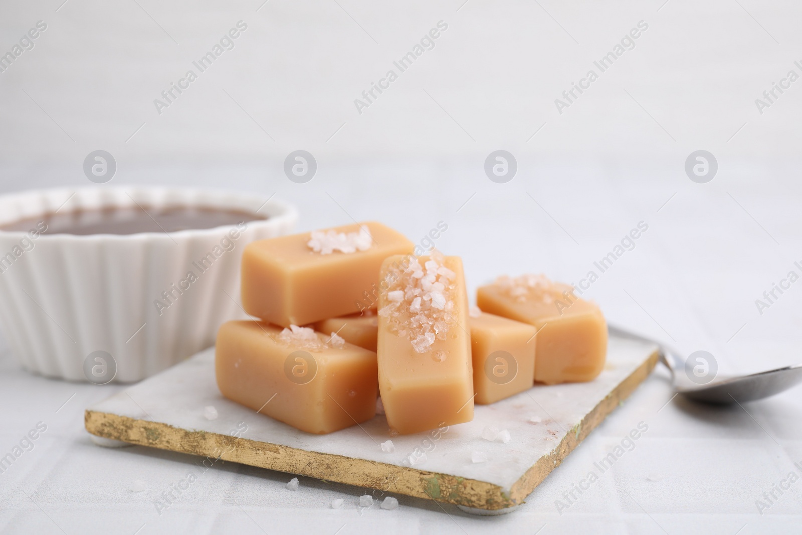 Photo of Delicious caramel candies with sea salt on white table