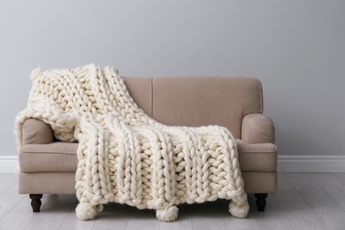 Soft knitted blanket on couch in living room. Interior element