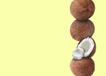 Image of Stack of fresh coconuts on pale light yellow background. Space for text