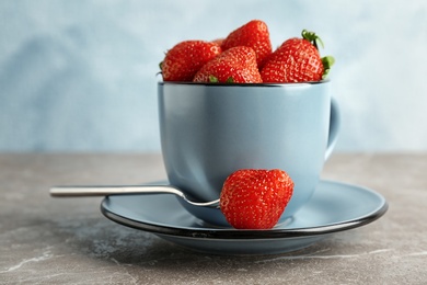 Photo of Cup with ripe red strawberries on table