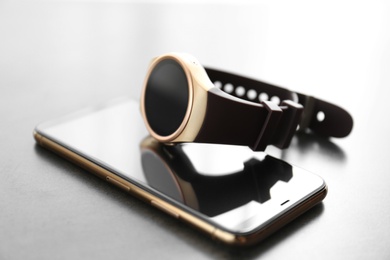 Photo of Stylish smart watch and phone on grey table, closeup